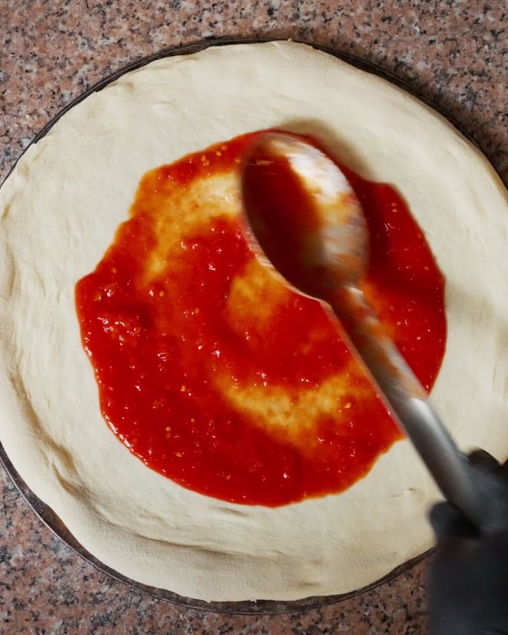 Giazzo: Pizzateig wird belegt, Nahaufnahme aus der Backstube